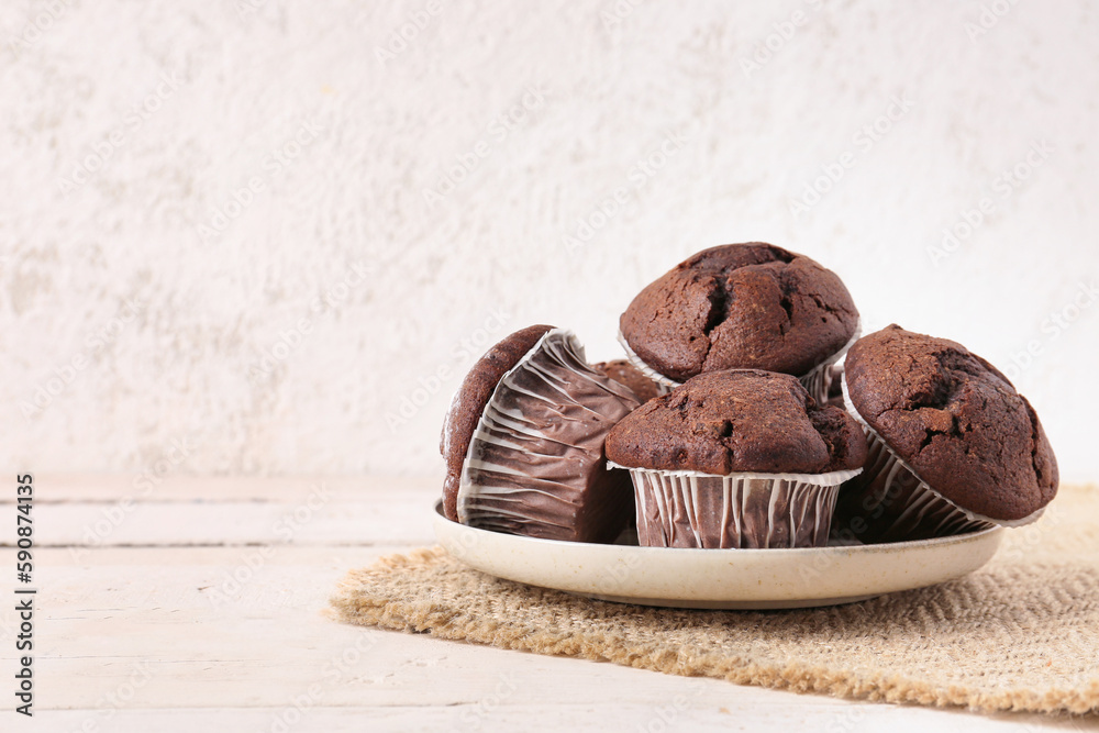 Plate with tasty chocolate cupcakes on table