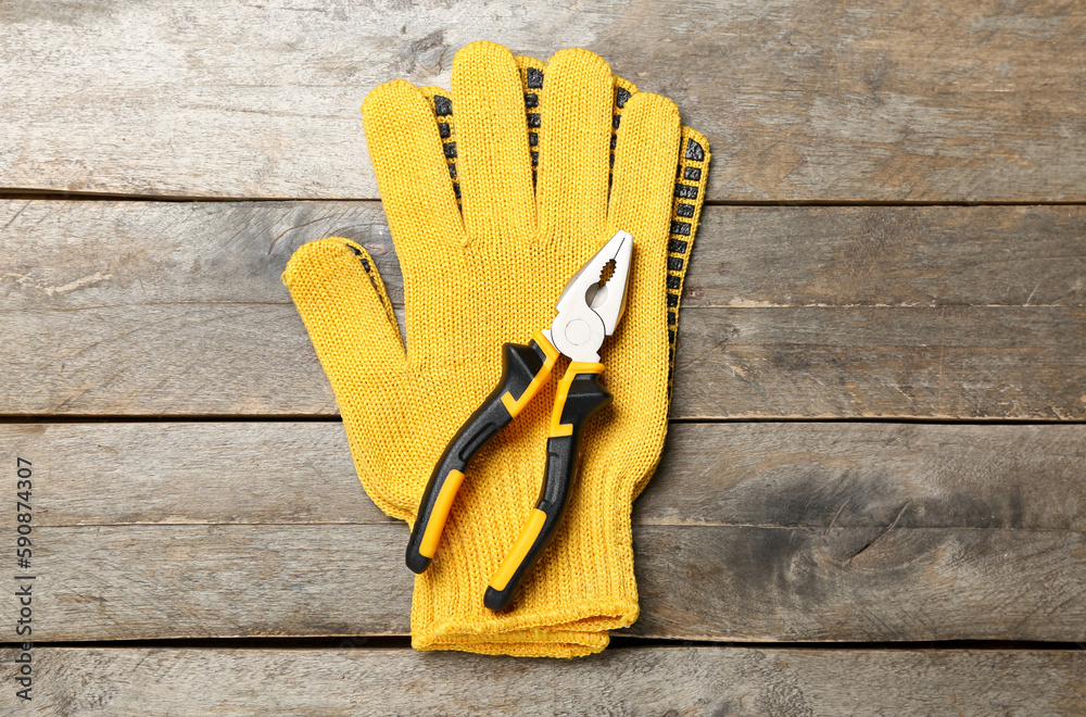 Pliers and gloves on wooden background