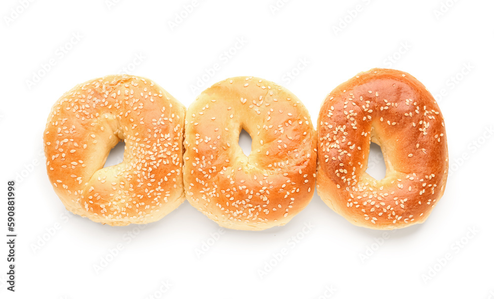 Tasty bagels with sesame seeds on white background