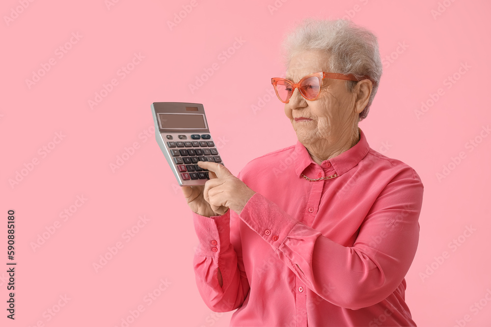 Senior woman using calculator on pink background