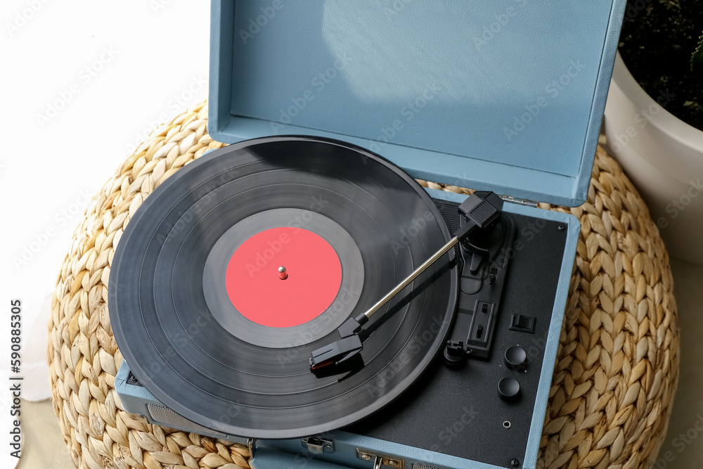 Record player with vinyl disk on pouf in room, closeup