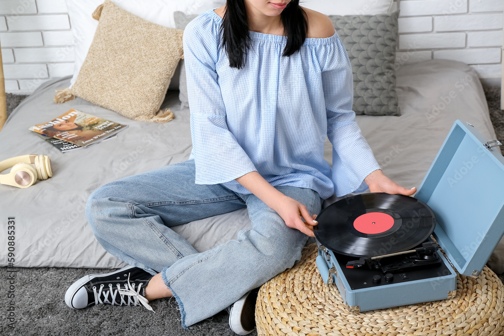 Young woman with record player in bedroom