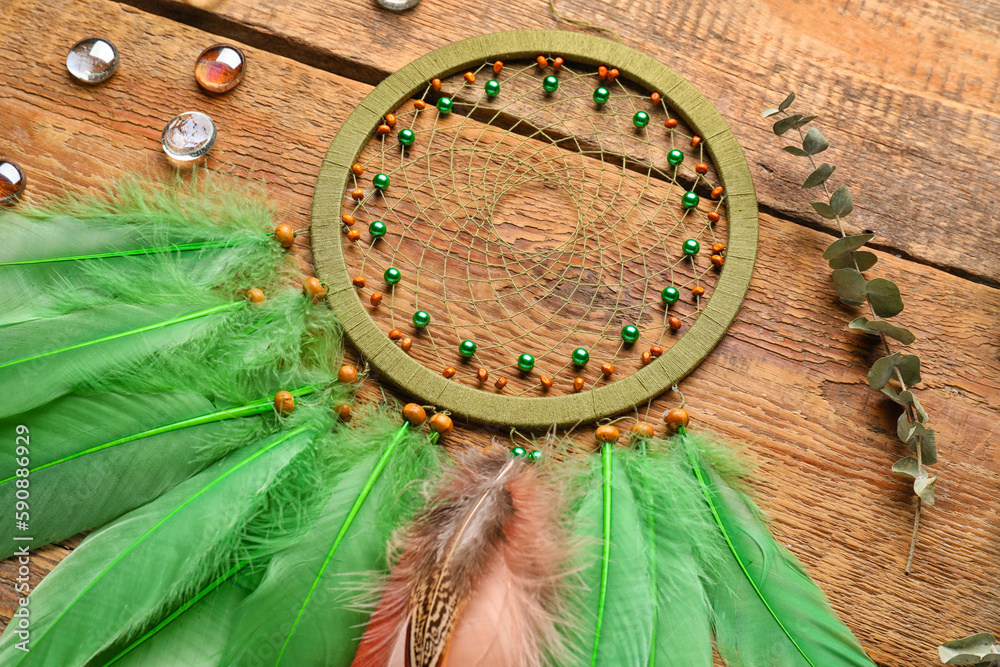 Dream catcher with glass stones and eucalyptus branch on wooden background, closeup