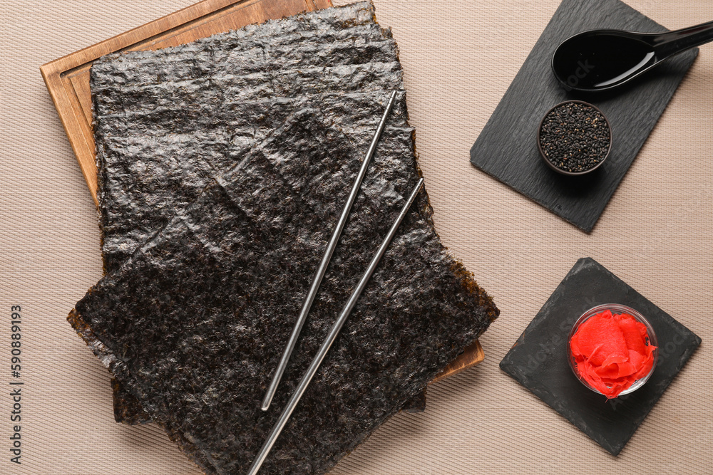 Board with nori sheets, sesame seeds, ginger and sauce on table