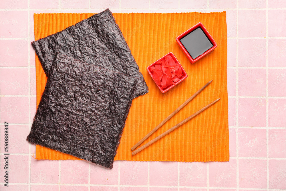 Nori sheets with sauce and ginger on pink tile background