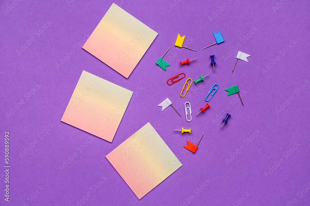 Sticky notes and paperclips on purple background