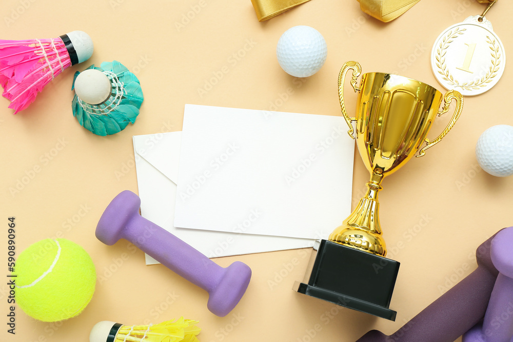 Blank card with gold cup, first place medal and sports equipment on beige background