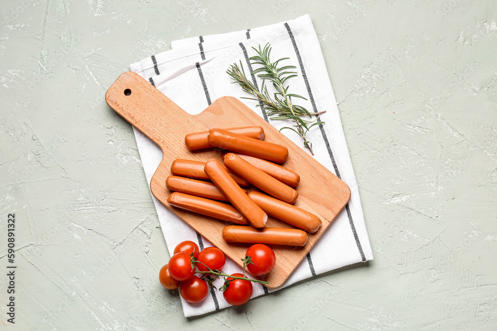 Wooden board with tasty sausages on light background