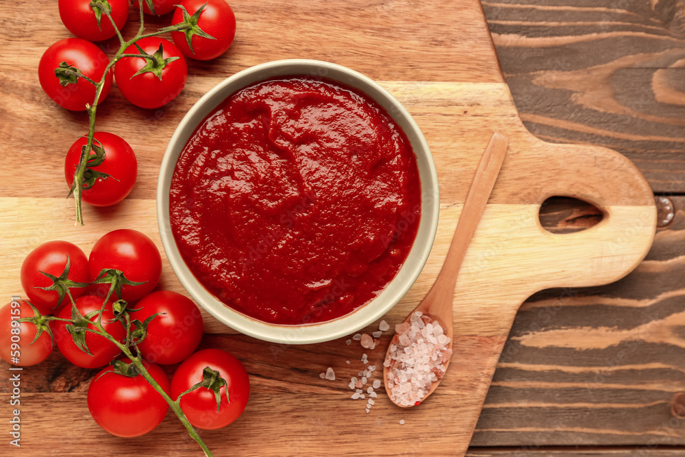 Bowl with tasty tomato paste and fresh vegetables on wooden background