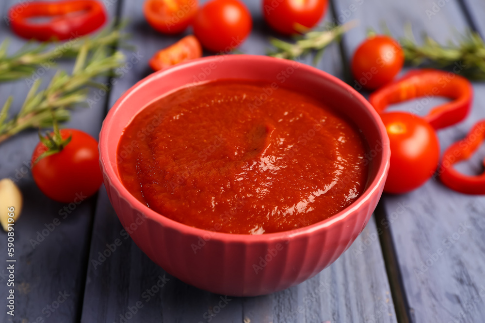 Bowl with tasty tomato paste on blue wooden background