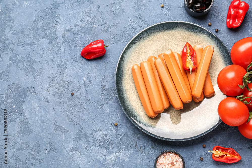 Plate with sausages, tomatoes and olives on blue background