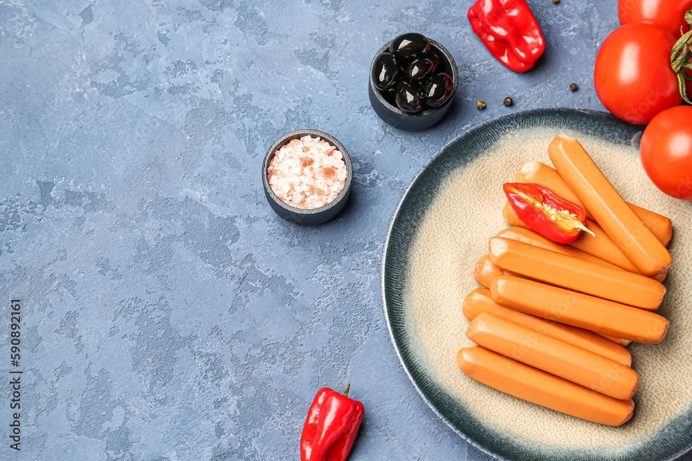 Plate with sausages, tomatoes and olives on blue background