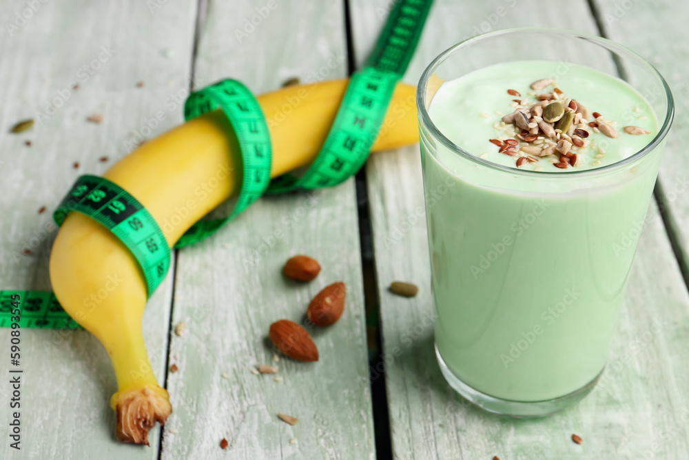 Banana, smoothie and green measuring tape on color wooden background. Diet concept