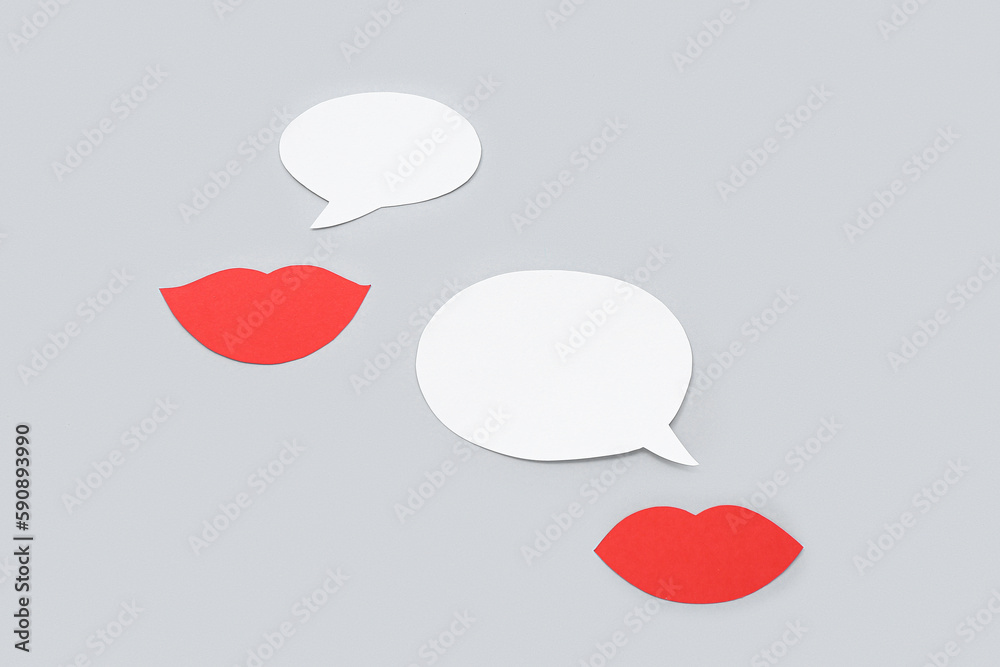 Paper lips with speech bubbles on grey background. Dialogue concept