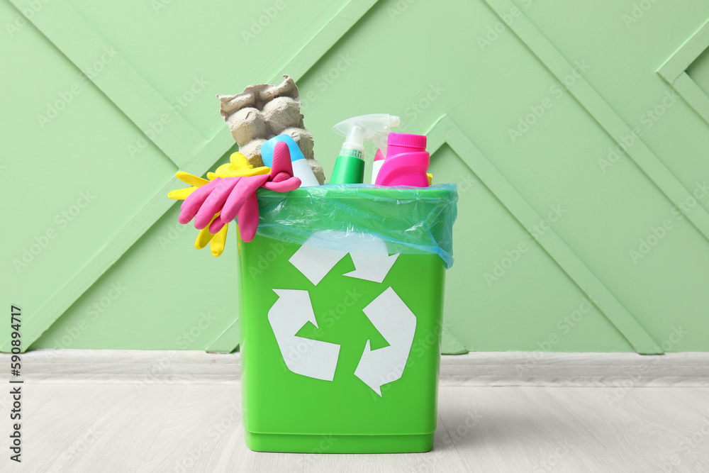 Recycling bin with garbage near green wall