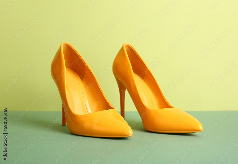 Pair of stylish high heeled shoes on green background