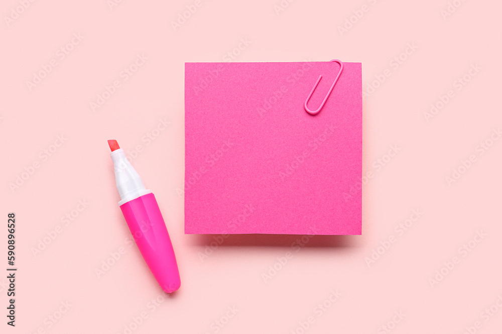 Pink sticky note with paper clip and marker on color background