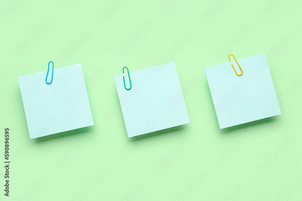 Sticky notes with paper clips on green background