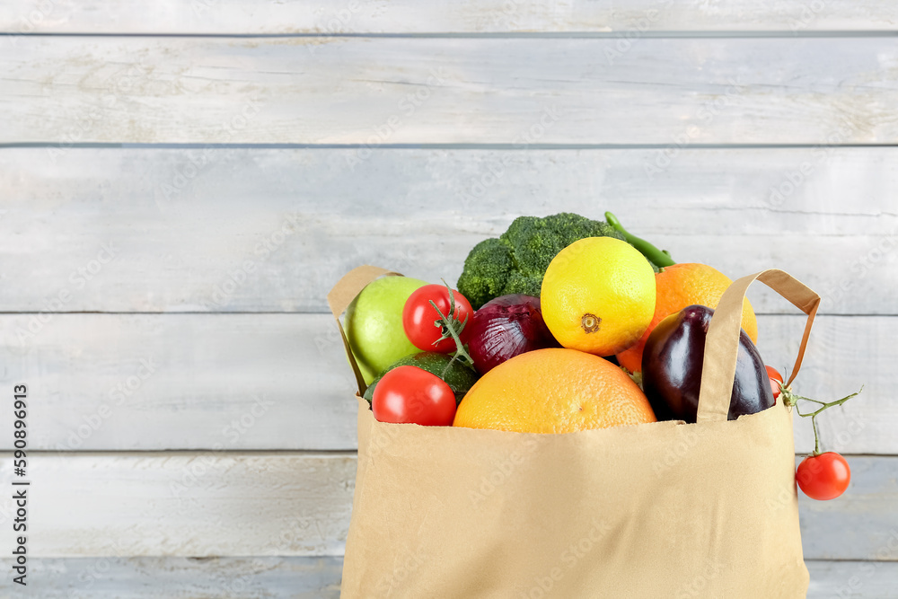 Paper bag with vegetables on wooden background