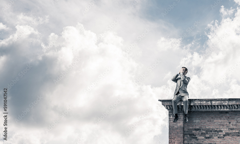 Young man on building edge do not want to see anything