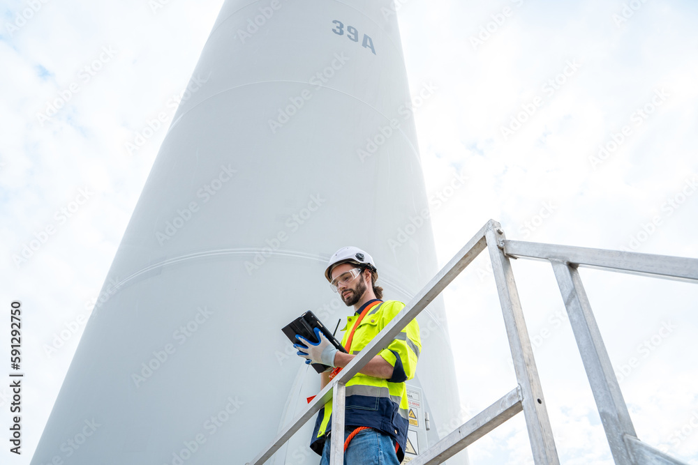 Engineer with technician are inspection work in wind turbine farms rotation to generate electricity 