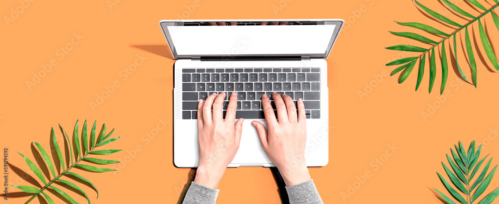 Person using a laptop computer with tropical leaves from above