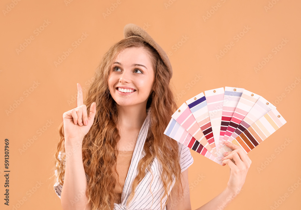 Female artist with paint color palettes pointing at something on beige background