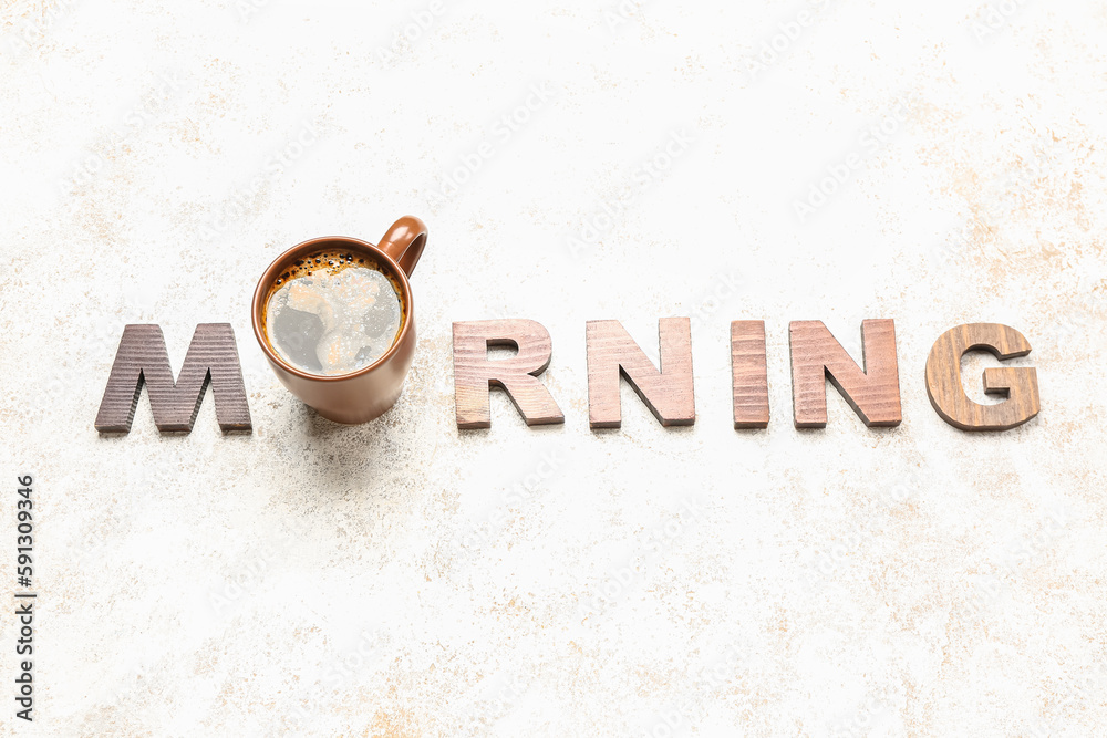 Word MORNING made of wooden letters and cup of coffee on light background