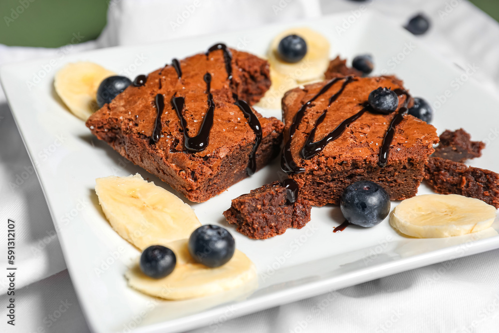 Plate with pieces of tasty chocolate brownie on table, closeup