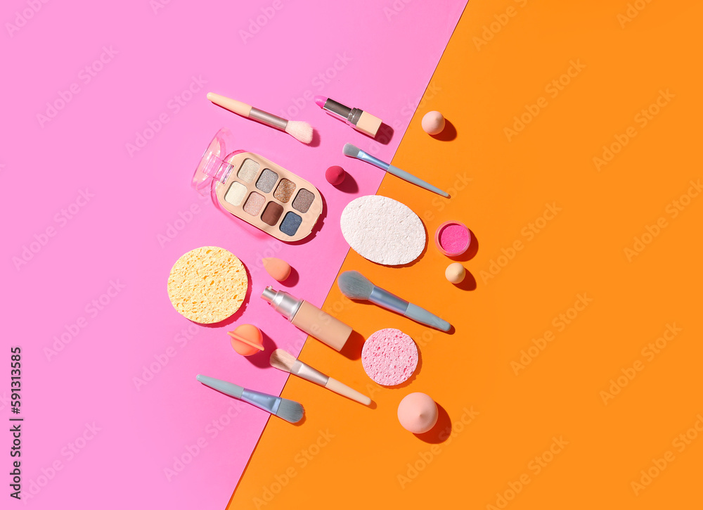 Decorative cosmetics with makeup brushes and sponges on color background