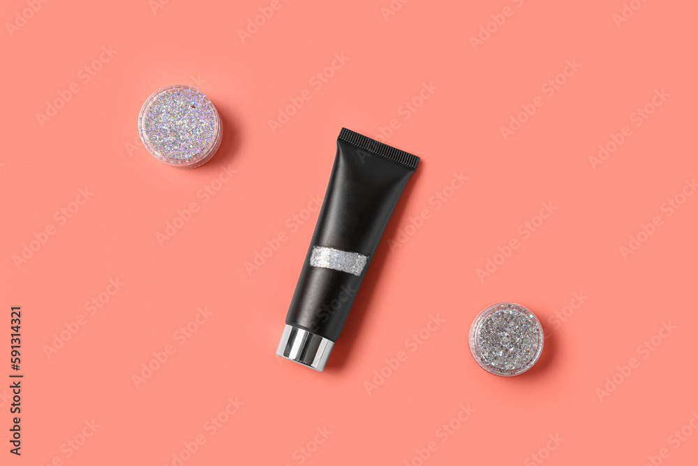 Tube with jars of silver glitter on pink background