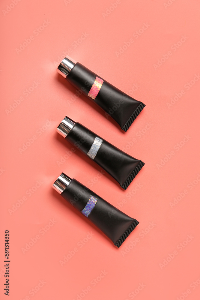 Tubes of glitter on pink background