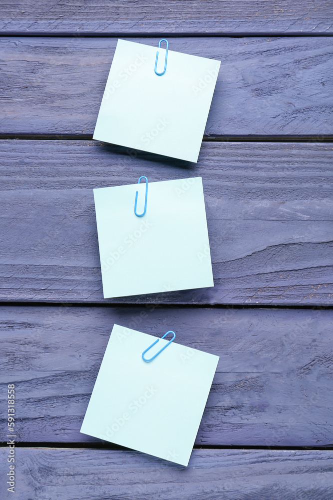 Sticky notes with paper clips on blue wooden background