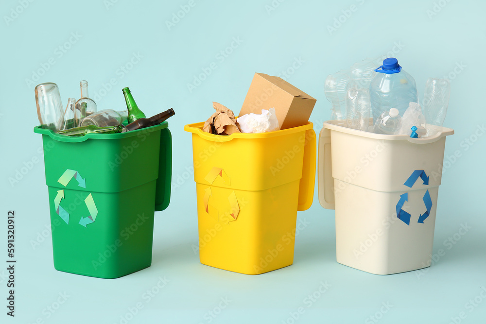 Containers with different types of garbage on light blue background. Recycling concept