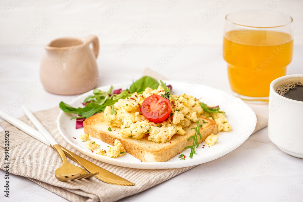 Plate with tasty scrambled eggs sandwich and salad on light background