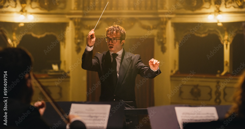 Cinematic Close Up of Conductor Directing Symphony Orchestra with Performers Playing on Stage During