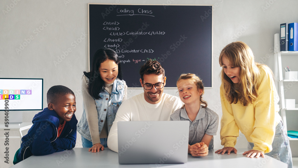 Coding school teacher showing a group of curious children how to write a code on a laptop