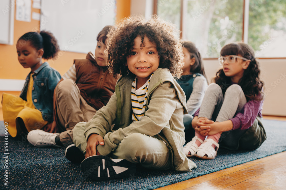 Boy sits in an elementary school class, he is looking at the camera