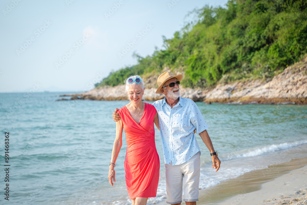 Happy senior couple walking together on beach on beautiful day,Authentic Senior Retired Life Concept