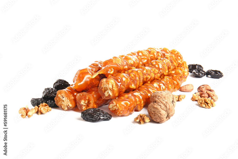 Tasty churchkhela, nuts and prunes on white background