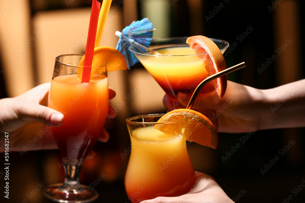 Women clinking glasses of tasty Tequila Sunrise on in bar