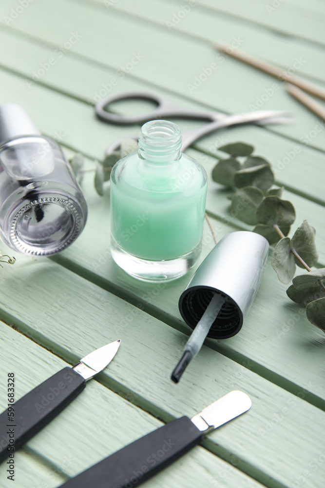 Bottles of cuticle oil and manicure instruments on color wooden background, closeup