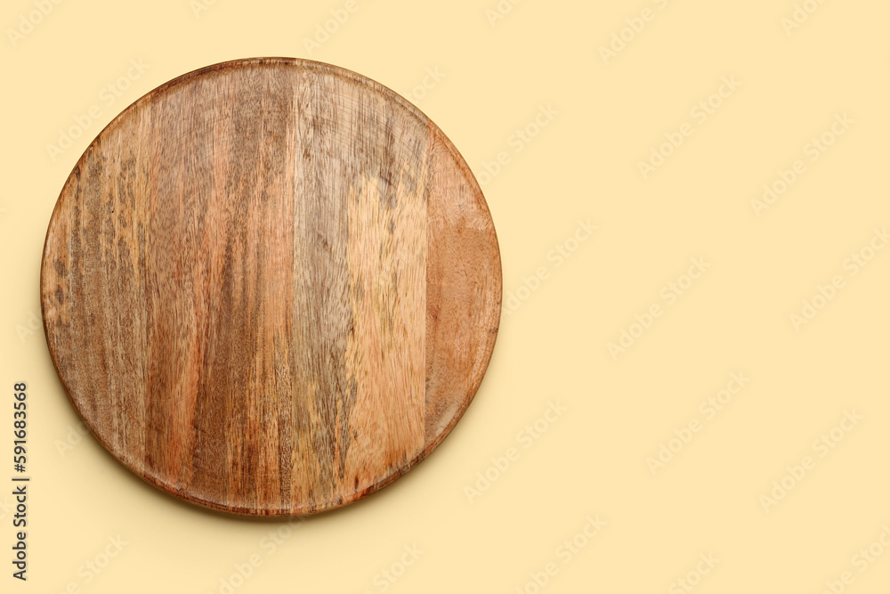 Round wooden board on yellow background