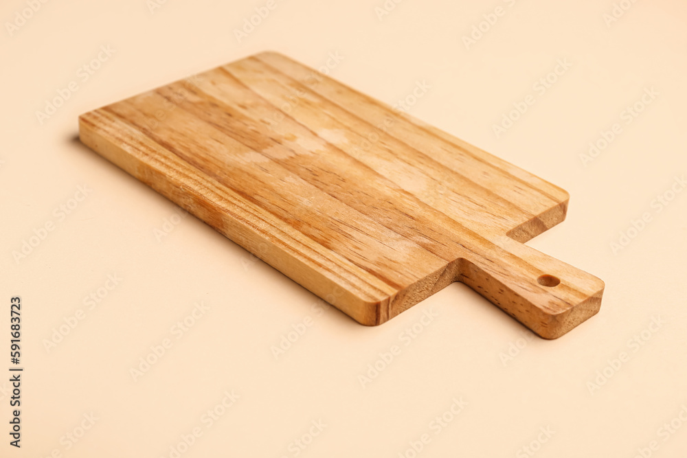 Wooden kitchen board on color background