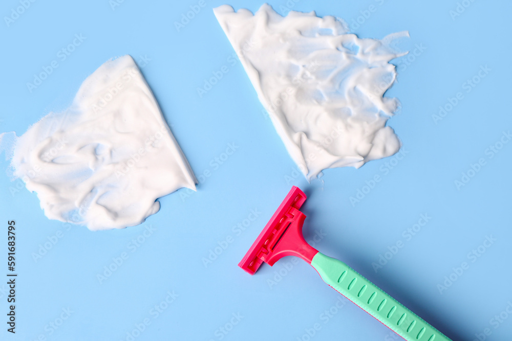 Safety razor and shaving foam on color background