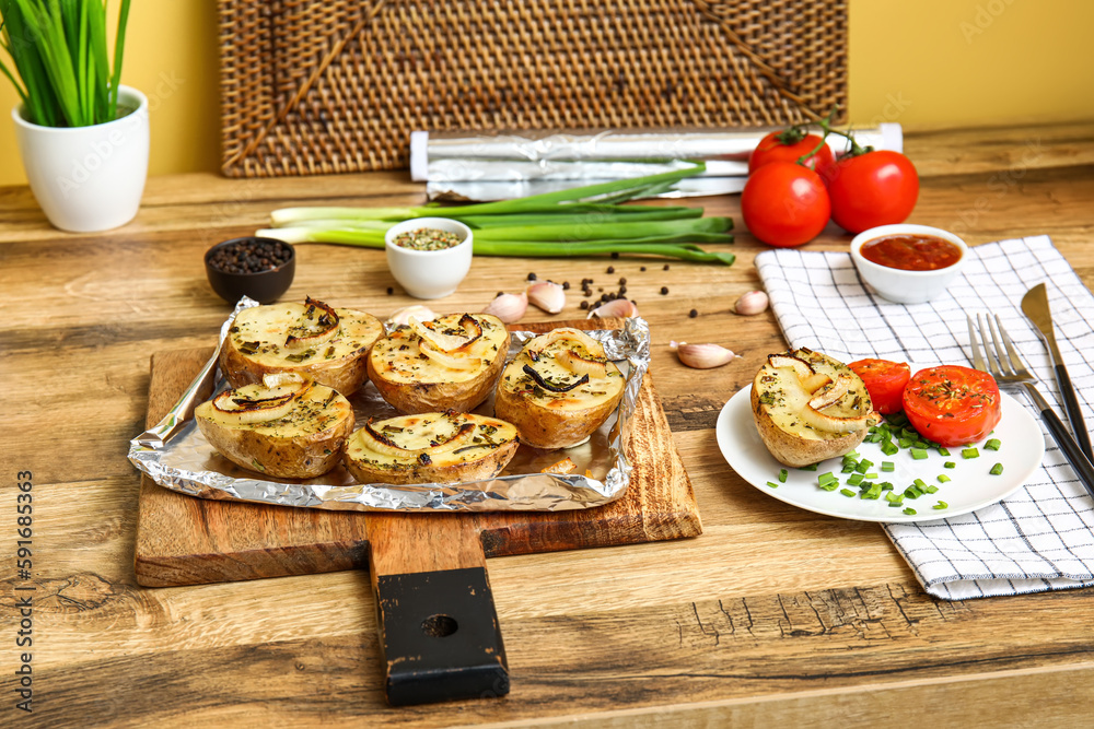 Cutting board with tasty baked potato, fresh vegetables and spices on wooden table in kitchen