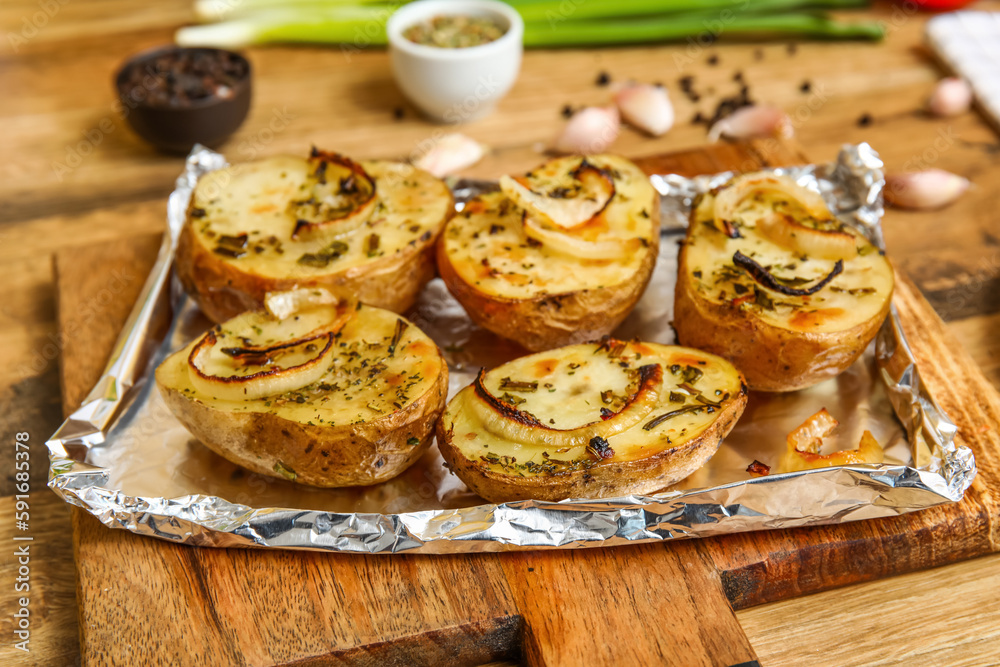 Wooden board with tasty baked potato on table, closeup