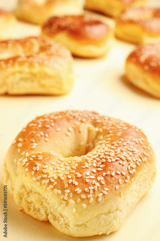 Tasty bagels with sesame seeds on beige background, closeup