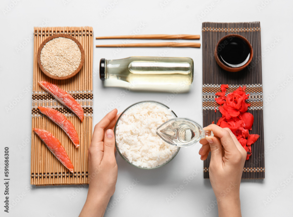 Female hands with ingredients for preparing tasty sushi rolls on white background