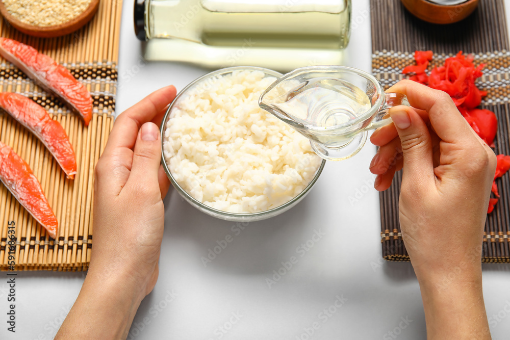 Female hands with ingredients for preparing tasty sushi rolls on white background, closeup